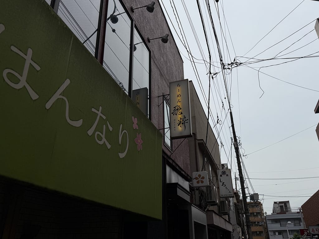 東京都大田区蒲田にある人気ラーメン店「らーめん飛粋 蒲田本店」の看板。建物の壁面に設置された縦長の看板に「らーめん飛粋」の文字が書かれている。