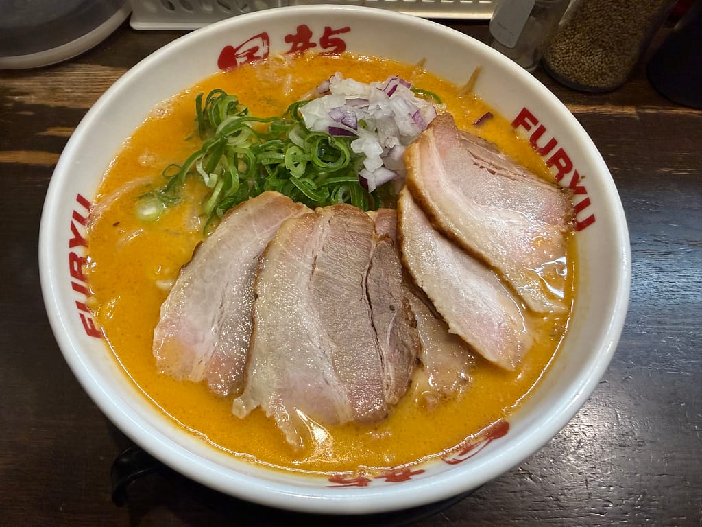 博多風龍 上野店の濃厚味噌チャーシューメン。濃厚な豚骨味噌スープに大判チャーシュー5枚、青ねぎと刻み玉ねぎをトッピングした豪華な一杯。