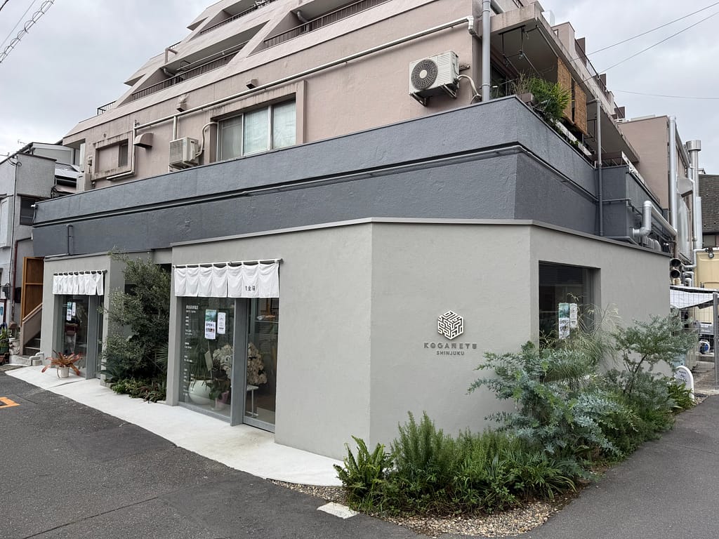 黄金湯 新宿店の外観。コンクリート調の建物に白い暖簾と「KOGANEYU SHINJUKU」のロゴが掲げられている。