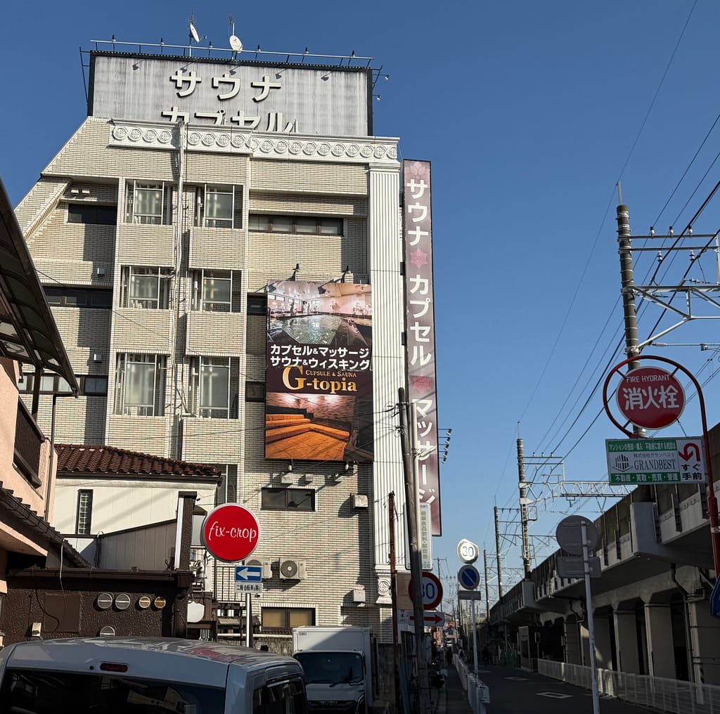 船橋駅近くにあるカプセル&サウナ「G-topia(ジートピア)」の外観、高層ビルに大きな看板が掲げられている