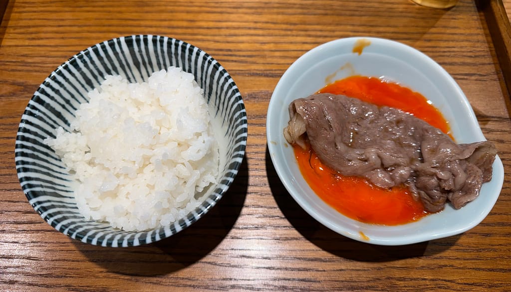 つけ麺専門店「あいだや」の黒毛和牛サーロインご飯。白ご飯と、卵黄入りのタレに浸かったサーロインが並ぶ。