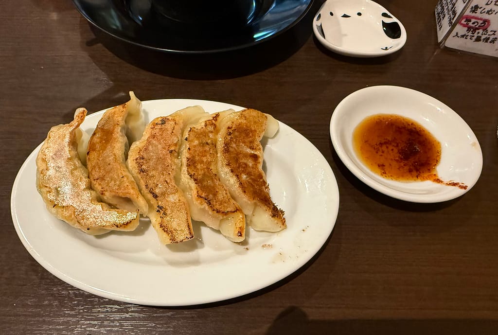 笹本為次郎商店の焼き餃子。こんがり焼かれた餃子5個と、別皿の特製タレが卓上に並ぶ様子。