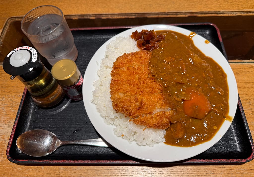 サウナ北欧のチキンカツカレー、サクサクのチキンカツに濃厚なカレーがかかり、ご飯と福神漬け、水と卓上調味料が並ぶ定食スタイルの一皿
