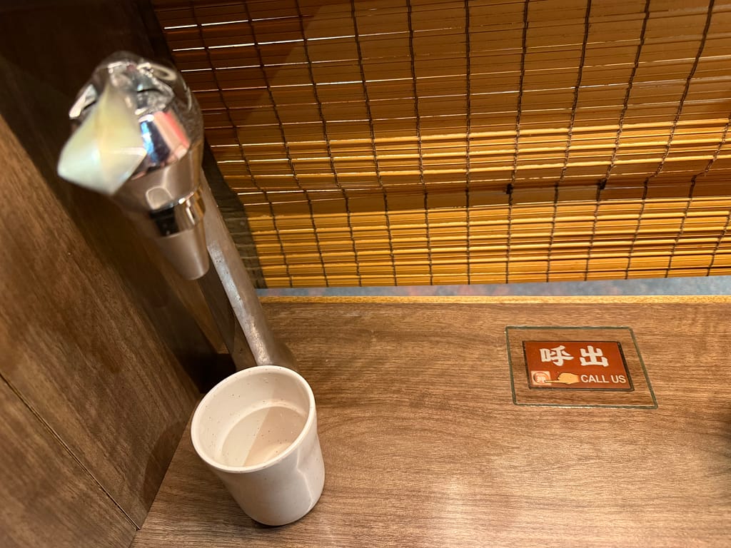 一蘭 上野アトレ店の味集中カウンター内。給水用の蛇口と紙コップ、呼び出しボタンが設置された個室風の席。