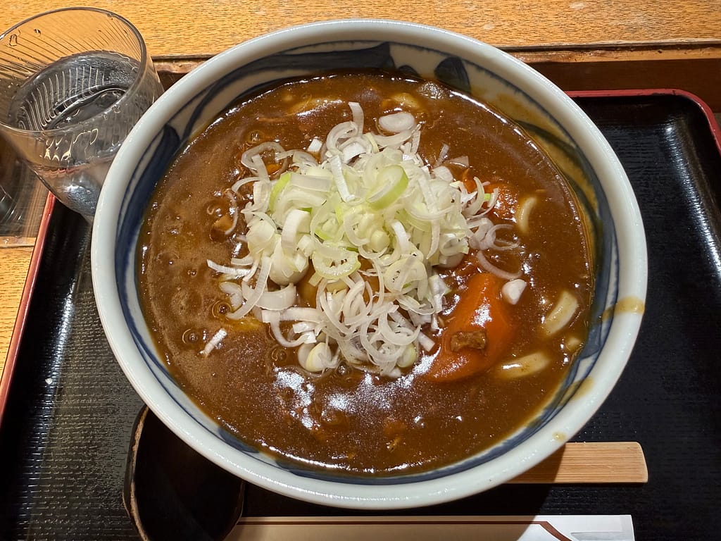 サウナ北欧のカレー南蛮うどん。熱々のカレー出汁がうどんによく絡み、たっぷりの長ねぎがアクセントになった食べ応えのある一品。