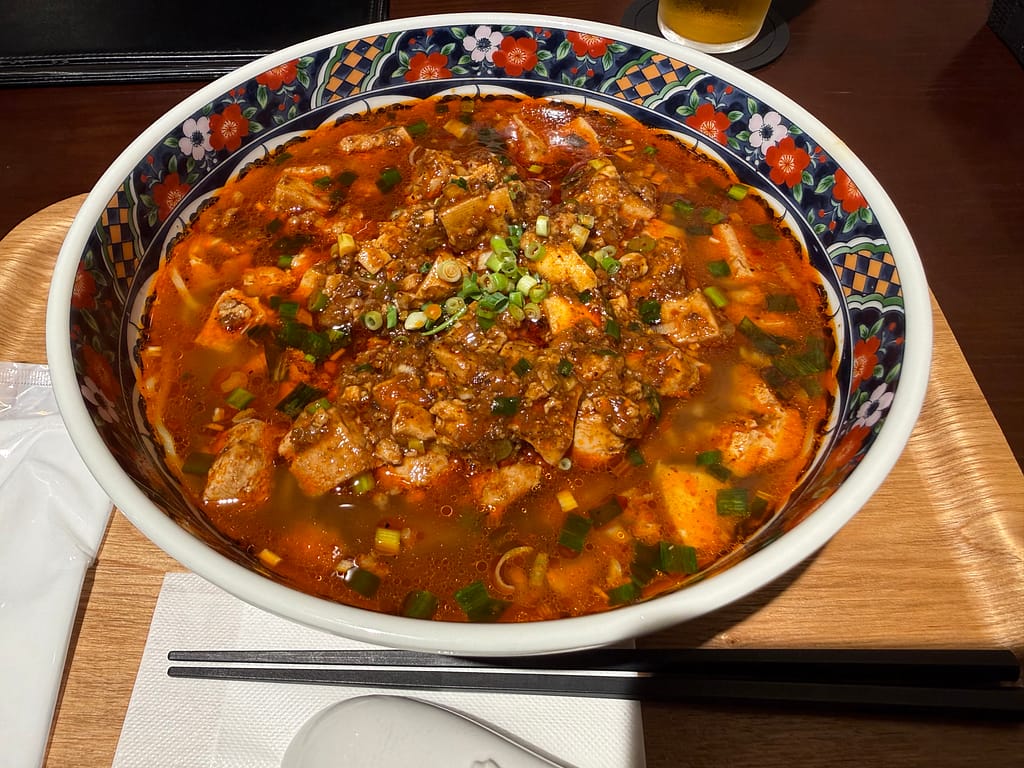 テルマー湯西麻布の麻婆豆腐湯麺。豆腐とひき肉を使った赤い麻婆あんが、麺を覆うようにたっぷりとかかった一杯。