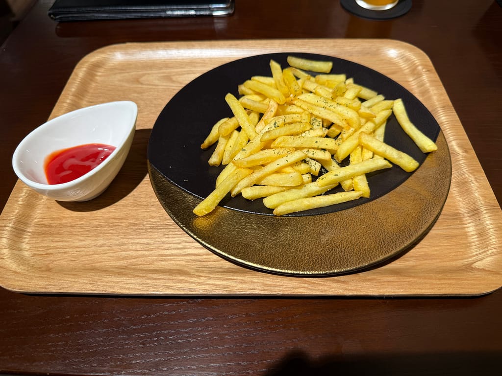 テルマー湯西麻布のポテト。揚げたてのフライドポテトを黒い皿に盛り付け、ケチャップを添えた一皿。
