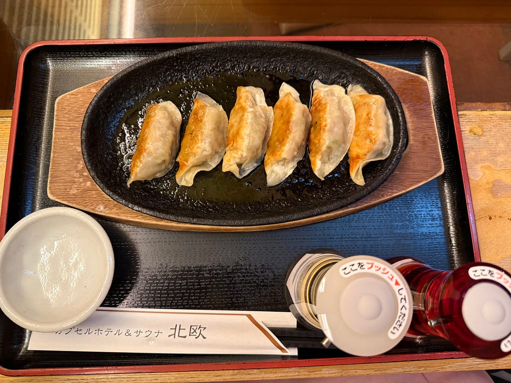 カプセルホテル&サウナ北欧(上野)の鉄板餃子。熱々の鉄板に6個の焼き餃子が並ぶ人気サイドメニュー。