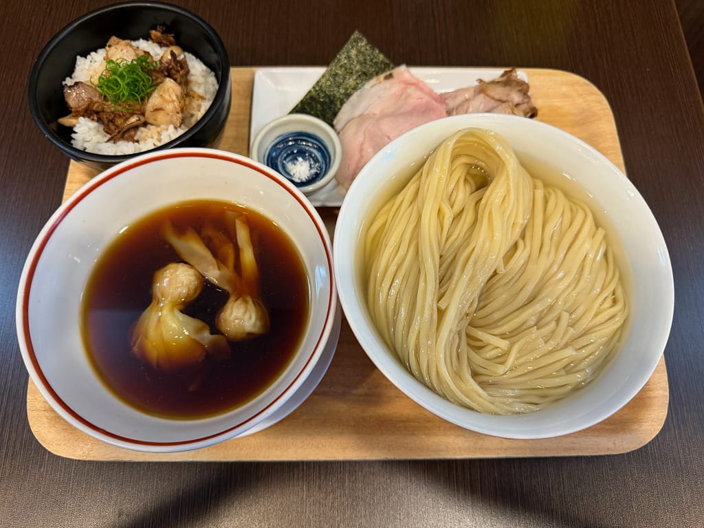 「千葉・船橋の人気店『とものもと』のつけ麺セット。白い器に盛られたストレート細麺、ワンタン入りの濃いめのつけ汁、チャーシューと海苔、小鉢の薬味、そして肉飯が木製トレーに美しく並んだ盛り付け写真。」