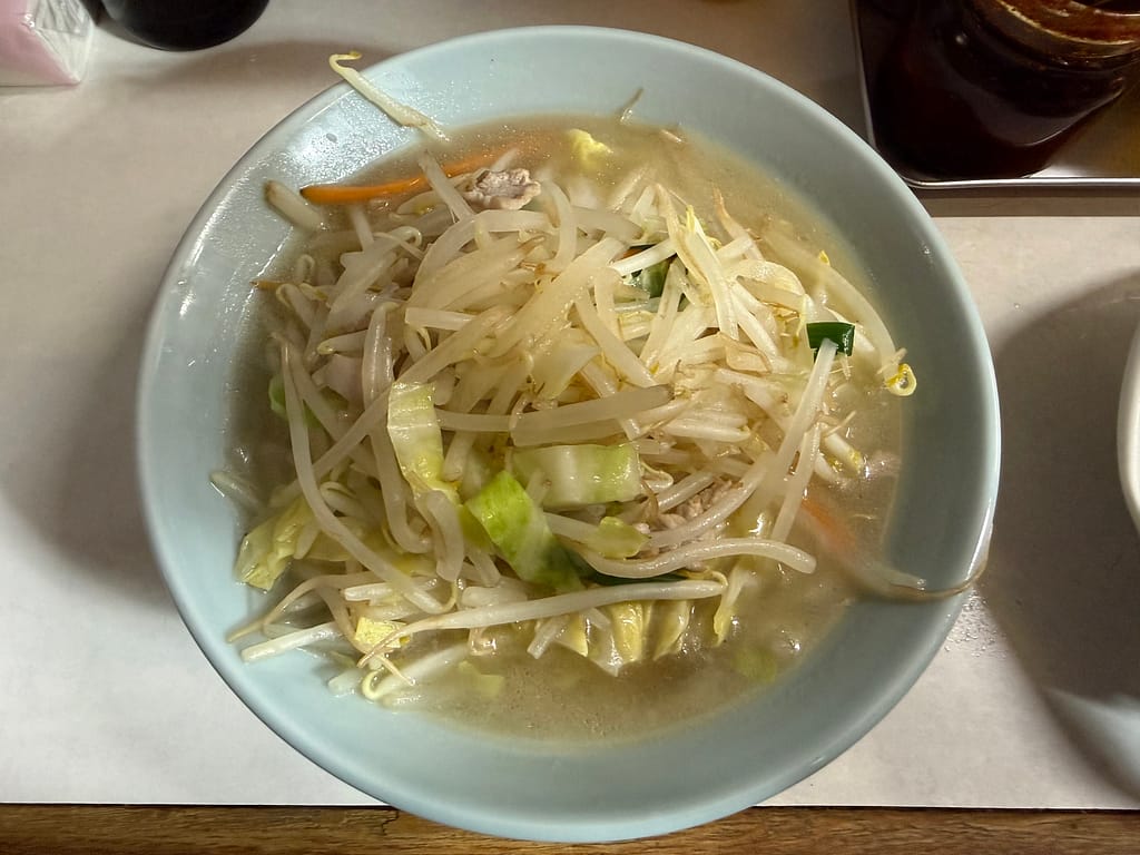 「珍々軒」の湯麺(タンメン)。たっぷりのもやしやキャベツなどの野菜が山盛りに盛られ、透き通った優しい塩スープが特徴的な一杯。上から撮影された構図で、昔ながらの町中華らしい温かみが伝わる。