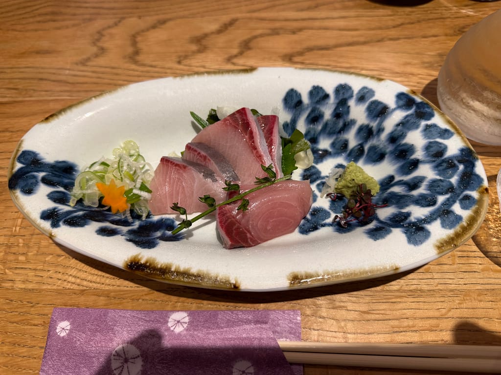 かるまる池袋の寒ブリ刺し。新鮮な寒ブリの刺身を薬味とわさびで味わう一品。