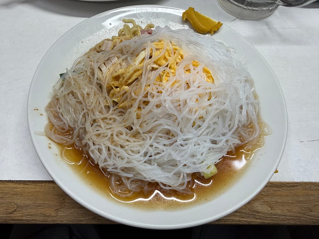 珍々軒の冷やし中華。細麺の上に春雨と錦糸卵をたっぷりのせ、醤油ベースのたれをかけた一皿。