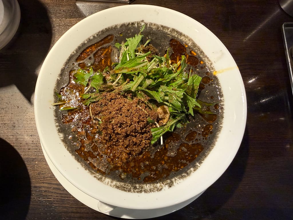 四川担担麺阿吽 湯島店の黒胡麻担担麺(大盛)。濃厚な黒ごまスープと肉味噌、水菜がのった一杯