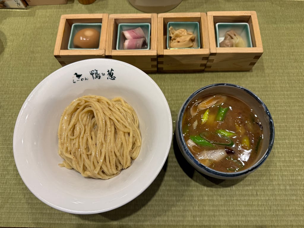 鴨to葱の特上鴨汁つけそば。ツヤのある中太麺と鴨の旨味が溶け出したつけ汁、青ネギが浮かぶスープに加え、味玉や鴨肉、メンマ、ワンタンが木箱に盛られた豪華なトッピング。