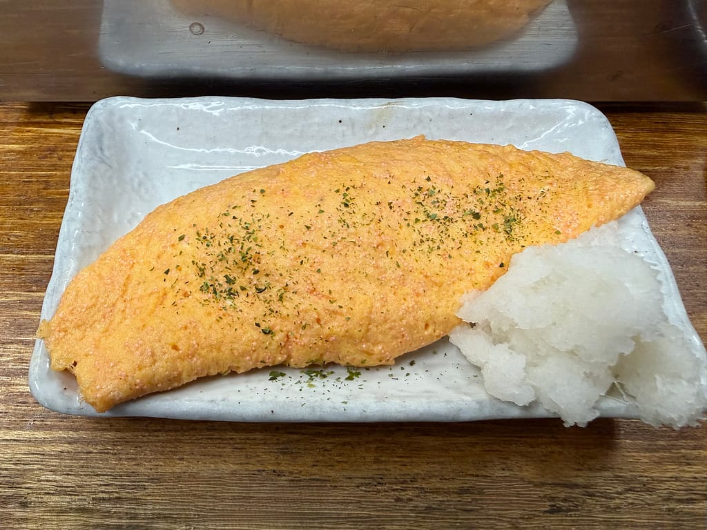 大衆酒場若林の明太オムレツ。ふわふわに焼き上げた玉子に明太子を合わせ、大根おろしを添えた人気メニュー。