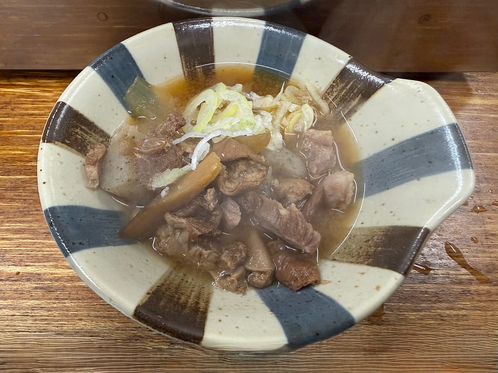 大衆酒場若林の煮込み。柔らかく煮込まれたモツとこんにゃく、野菜を醤油ベースのスープで仕上げた定番人気メニュー。