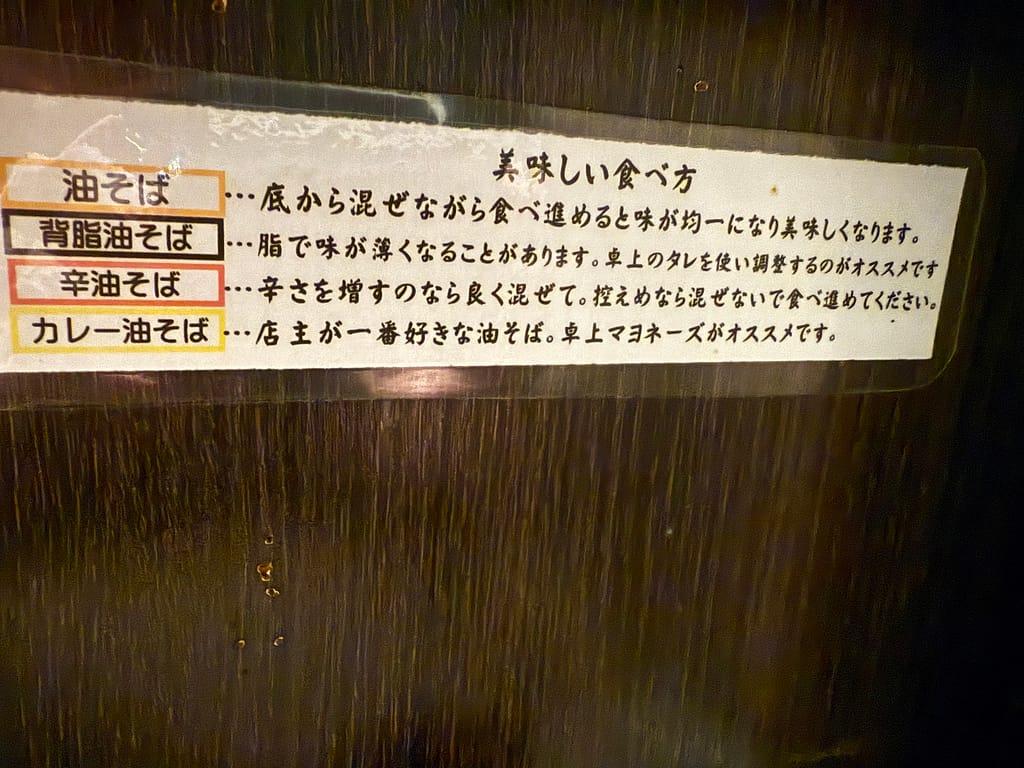 「油カダブラの油そば・背脂油そば・辛油そば・カレー油そばの美味しい食べ方を説明した店内の案内表示。混ぜ方や調味料の使い方が書かれている。」