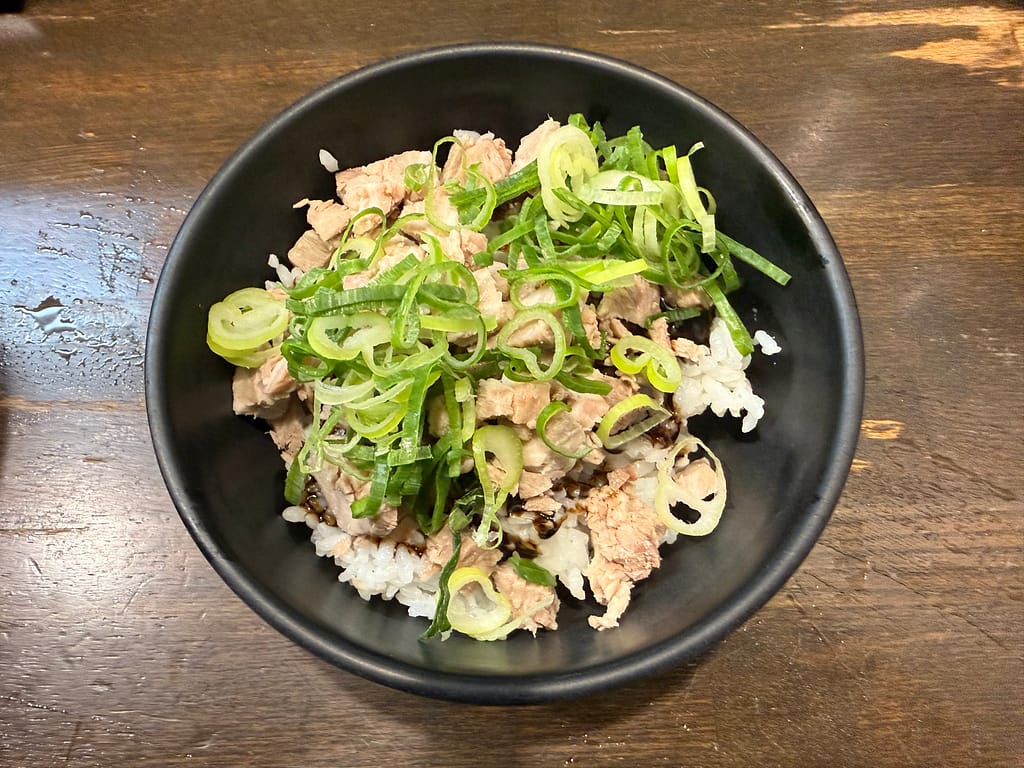 博多風龍の黒マー油ご飯。白ご飯の上に細かく刻んだチャーシューとたっぷりの青ネギを盛り付け、黒マー油をかけたサイドメニュー。