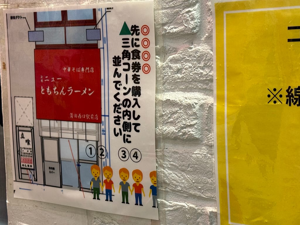 新橋ニューともちんラーメン蒲田西口駅前店の並び方案内。食券購入後に店内の角を曲がり外で並ぶルールが図解で説明されている掲示物。