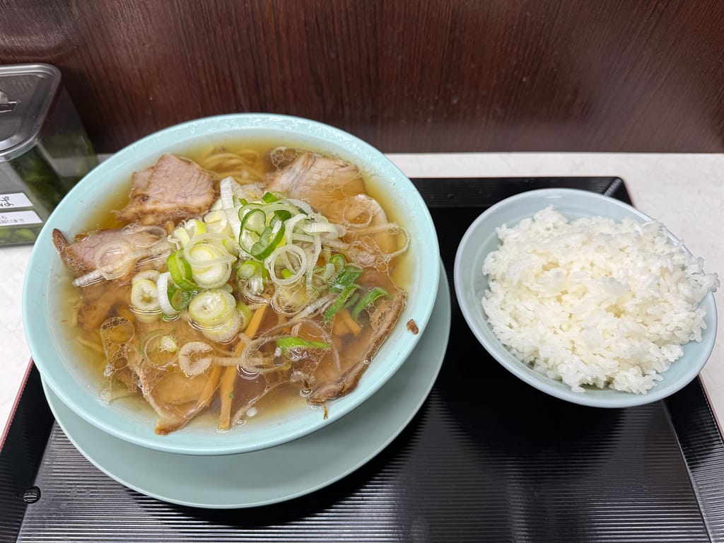 新橋ニューともちんラーメン蒲田西口駅前店の中華そばとご飯。透き通ったスープにチャーシューとネギがのり、無料の白ご飯がセットになったコスパの高い一杯