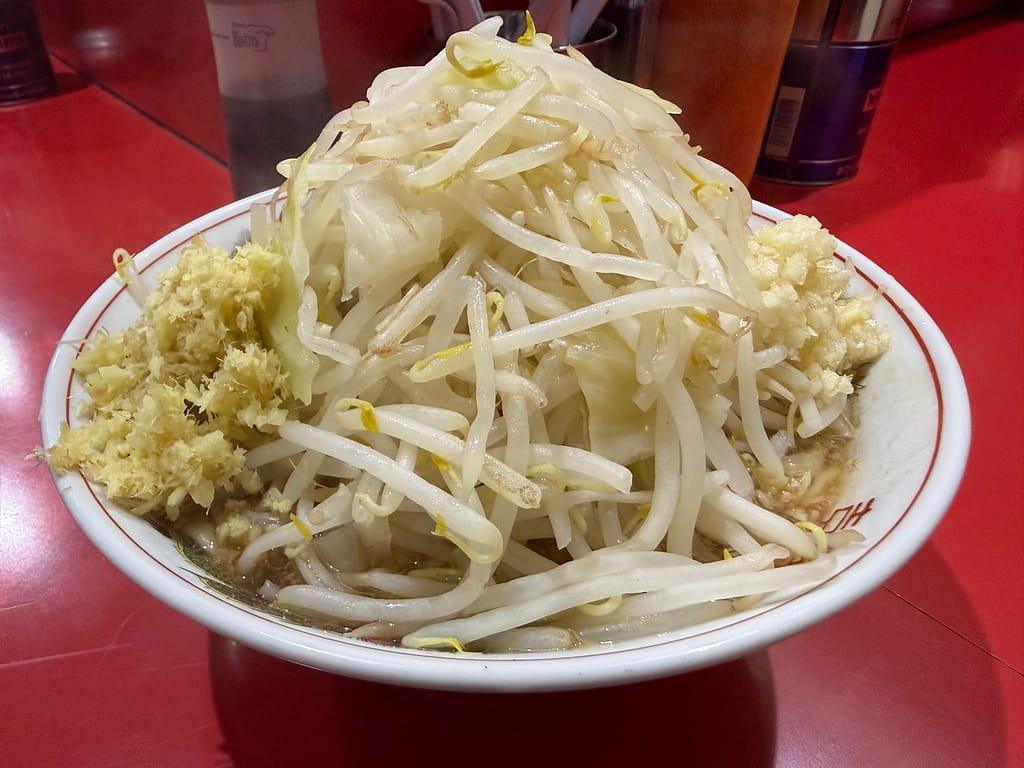 ラーメン二郎千葉店の小ラーメン。山盛りのもやしとキャベツにニンニクとショウガが添えられたボリューム満点の一杯。