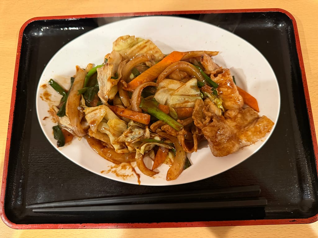 サウナセンター稲荷町のレストランで提供されるスタミナ炒め。豚肉とキャベツ、玉ねぎ、にんじん、ピーマンなどの野菜を甘辛いタレで炒めた、ご飯にもサウナ後にも相性抜群の一皿。