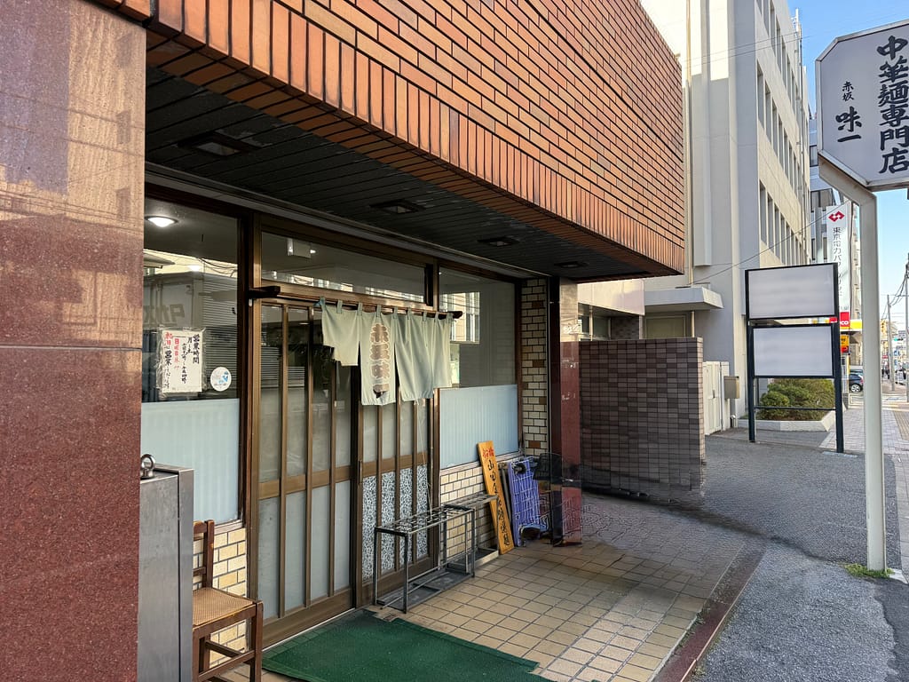 赤坂味一の店舗外観。年季の入った暖簾が掛かる入口と、中華麺店の看板が目を引く船橋の老舗ラーメン店。