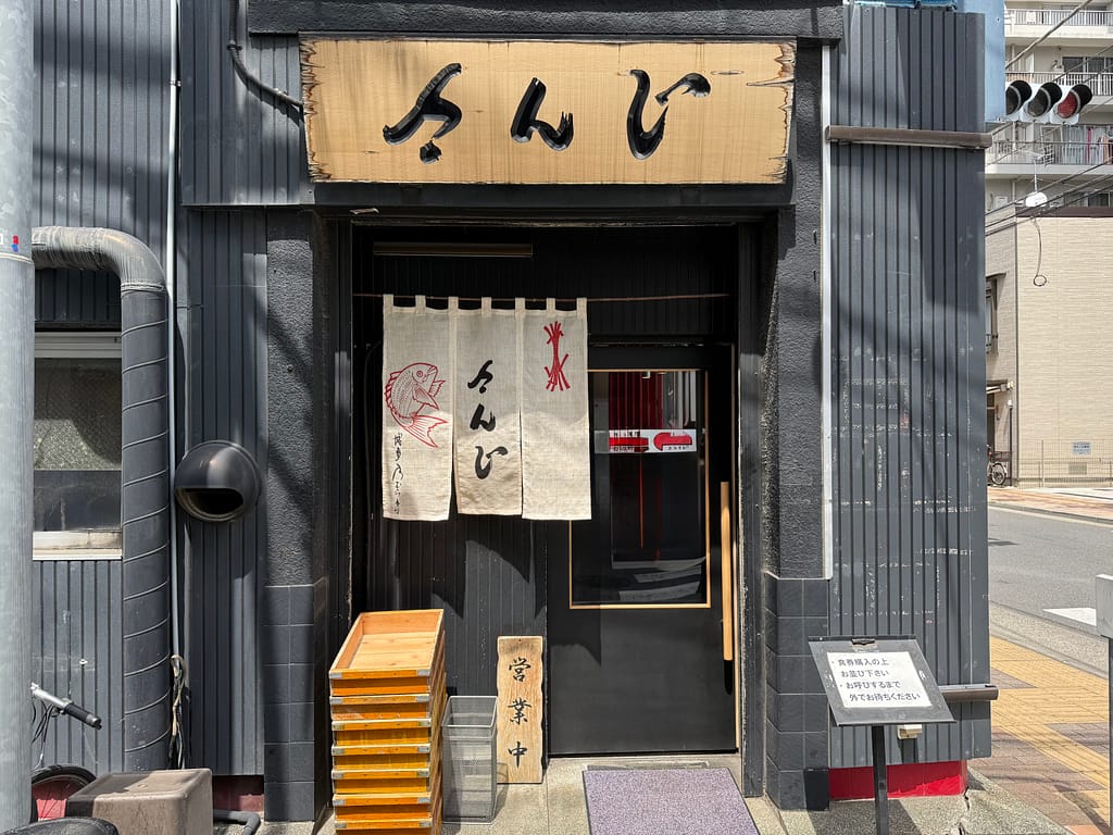 上野の煮干しラーメン店「さんじ」の外観。木製看板とのれんが特徴的な店舗入口