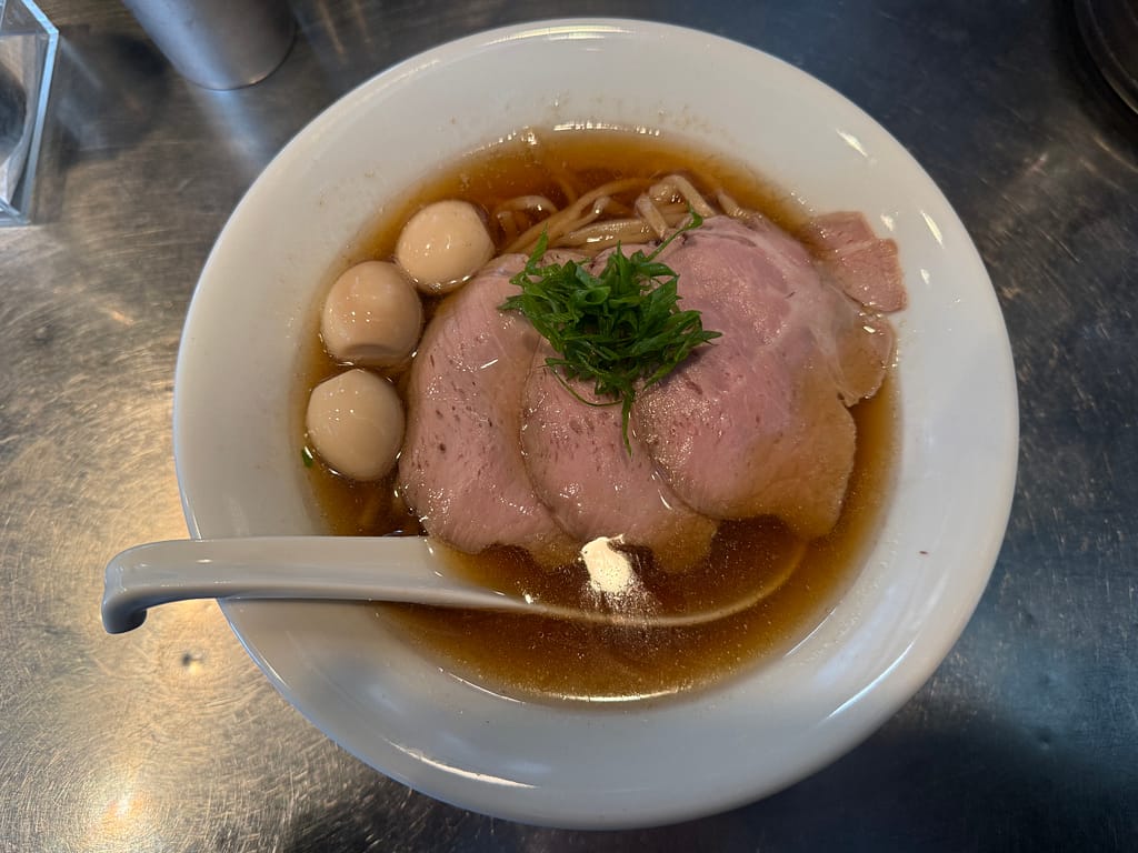上野・さんじの帆立煮干。ロースチャーシュー3枚とうずら3個をのせた、琥珀色のスープが美しい煮干しラーメン。
