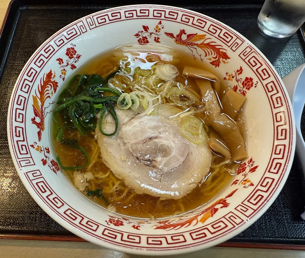 「船橋グランドサウナのレストランで提供される昔ながらの中華そば。鶏ガラ醤油の澄んだスープに、中央に大きなチャーシュー、メンマ、ネギ、ほうれん草が盛られた一杯。」