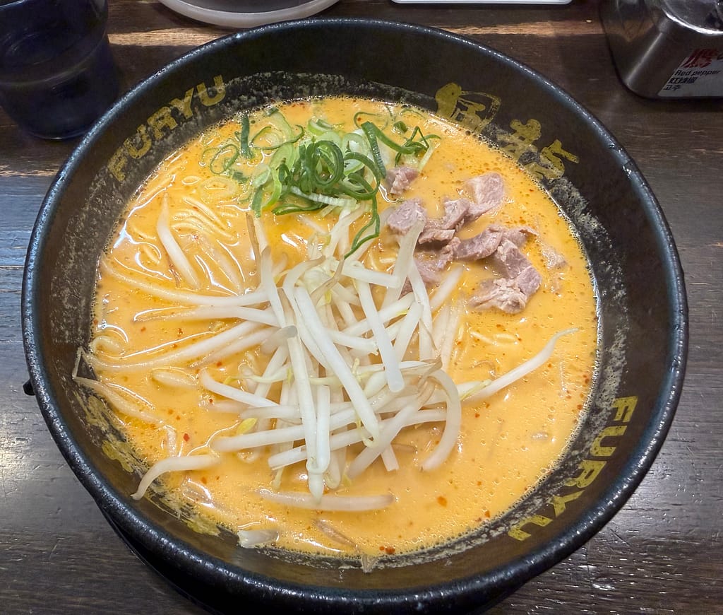 博多風龍 上野店の辛味噌とんこつラーメン。オレンジ色の濃厚スープに極細麺、もやし、ねぎ、チャーシューがのった一杯。