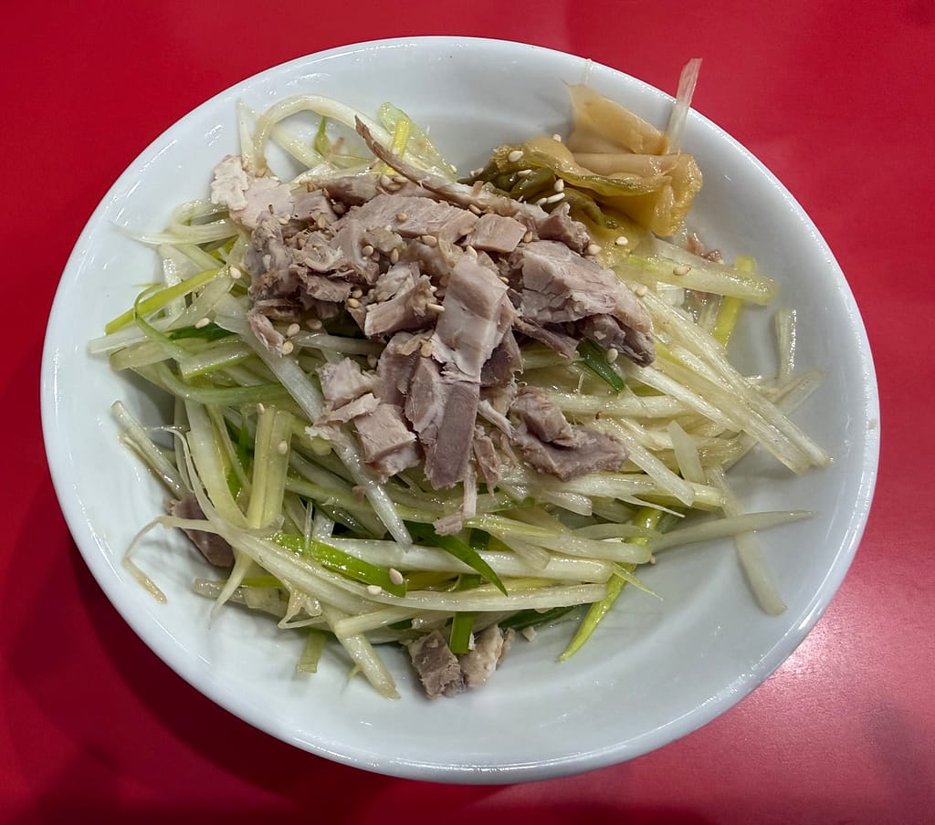 ラーメンかいざん 船橋店のネギチャーシュー丼。細切りネギと刻みチャーシューがたっぷり盛られたサイドメニューを赤いカウンター席で撮影。