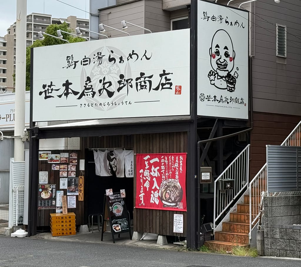 笹本為次郎商店の大きな看板と入口外観。白い看板に店名が大きく描かれ、赤い暖簾やメニュー看板が並ぶ千葉県の鶏白湯ラーメン店。