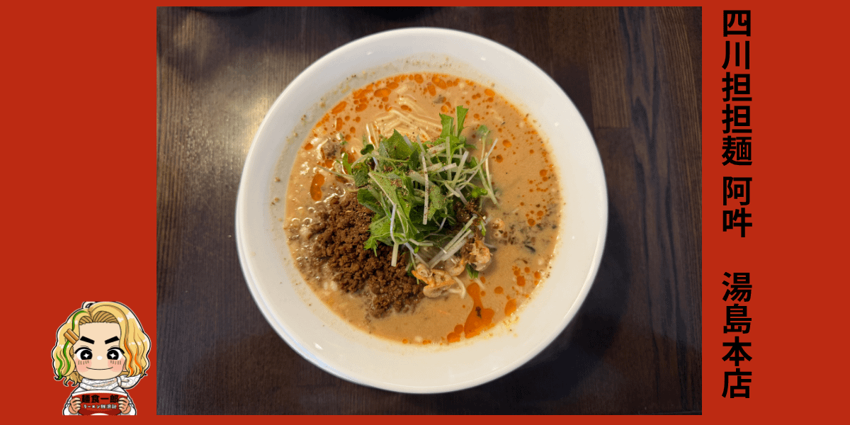 白い器に盛られた担々麺。スープの表面には赤い辣油が美しく広がり、中央にはひき肉と水菜、白髪ねぎが彩りよく盛り付けられている。濃厚な白ごまスープと香ばしい香りが食欲をそそる一杯。