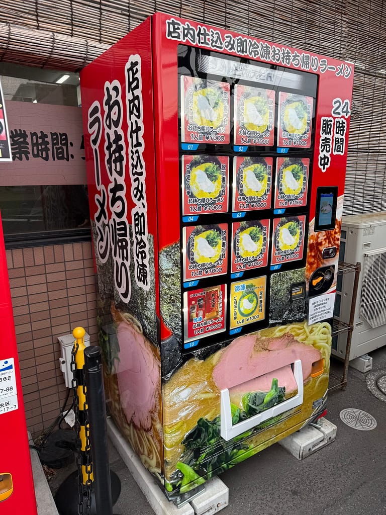 「杉田家 千葉祐光店の持ち帰りラーメン自動販売機。24時間購入可能な冷凍家系ラーメンが並ぶ店舗前の設備」
