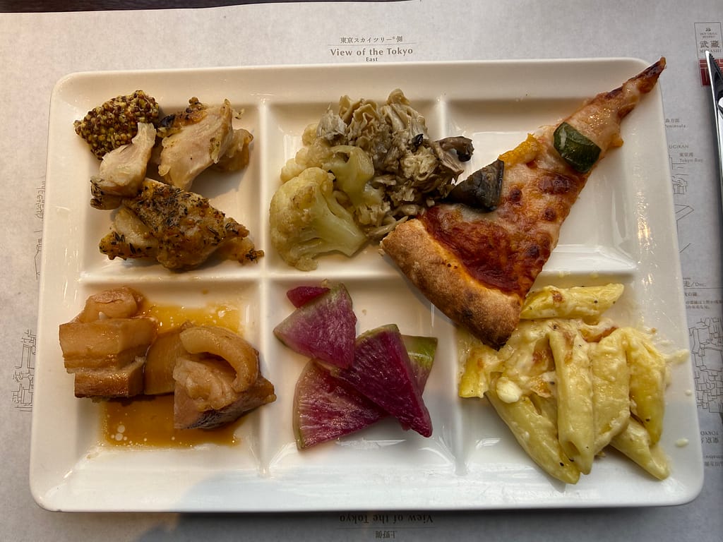 浅草ビューホテル スカイグリルブッフェ武蔵の洋食プレート。ピザやパスタ、鶏肉料理、温野菜などを盛り付けた一皿。