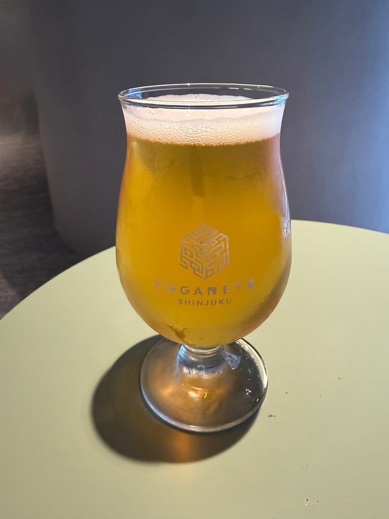 黄金湯 新宿店のオリジナルクラフトビール。KOGANEYU SHINJUKUのロゴ入りグラスに注がれている。