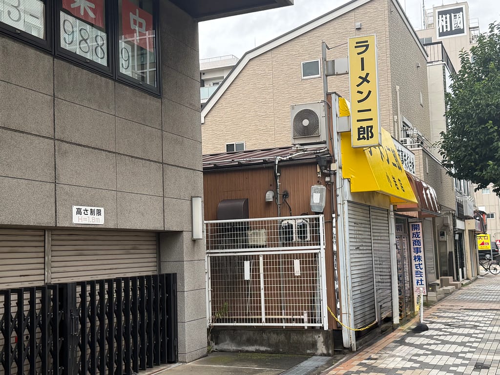 ラーメン二郎 小岩店の店舗外観。路地沿いに黄色い「ラーメン二郎」の看板が掲げられている。
